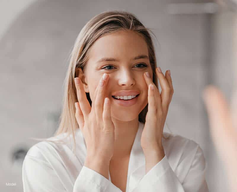 woman adding cream under her eyes